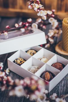 Spring collection of handmade chocolate bonbons candies and cherry flowers decoration on rustic wooden background.