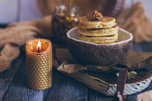 Stack of delicious pancakes with honey, nuts on wooden background.