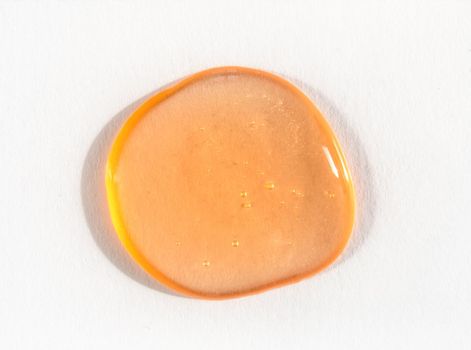 Orange cosmetics or antiseptic gel, cleaner or serum drop on white background. Colorful amber slime with air bubbles in the sunlight. High contrast trendy photo. Health protection concept