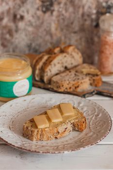 Ghee butter in glass jar and sliced bread on table. Healthy eating, breakfast.