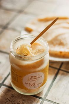 Ghee butter in glass jar and sliced bread on table. Healthy eating, breakfast.