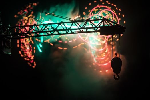 Abstract Industrial background with construction crane silhouette over amazing night sky with fog and backlight. Tower crane against the foggy sky at night. Industrial skyline. Selective focus