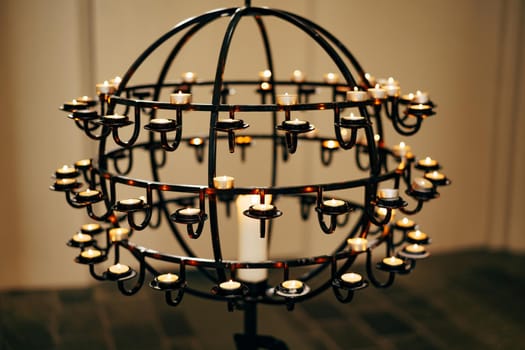 Votive candles stand on a ball-shaped stand in a church. High quality photo