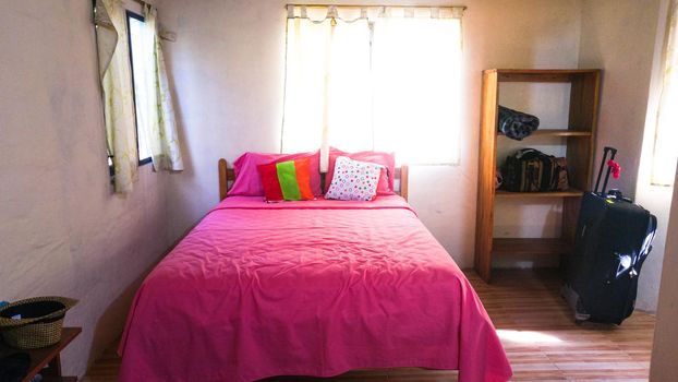 The rustic style of a room in shades of white and pink with a wooden bed and a beautiful view in Montanitas - Ecuador