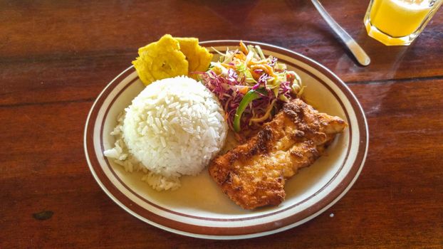 Rice with fried fish and salad, homemade food from Ecuador - Montanita