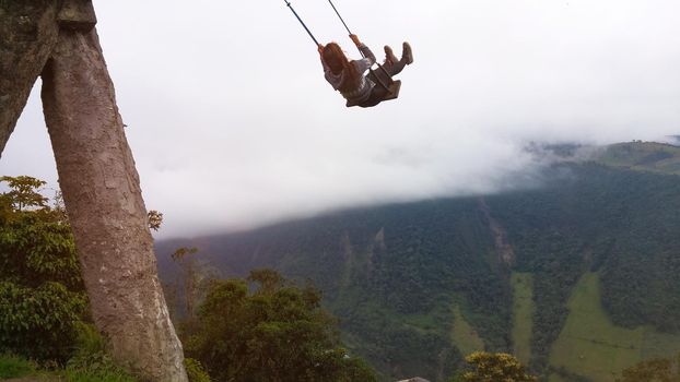 Woman enjoying the End of the World swing up the mountains at La Casa del arbol, Banos, Ecuador