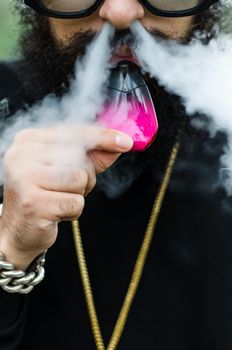 Close-up of a man with an electronic cigarette, man with leafy beard, gold chain and sunglasses