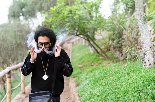 Men with beard vaping and doing tricks with smoke outdoors and wearing sunglasses