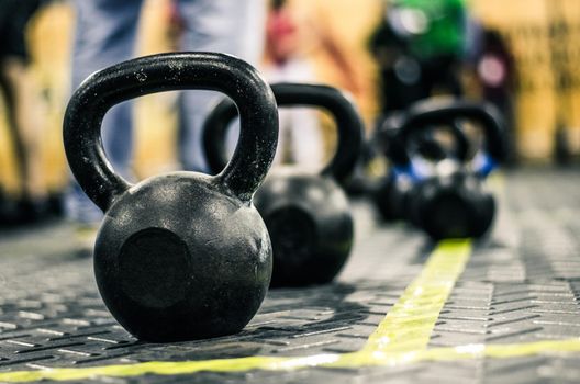 Different sizes of kettlebells weights lying on gym floor. Equipment commonly used for crossfit training at fitness club