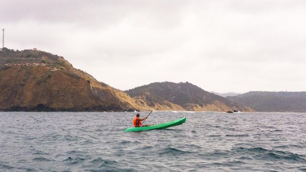 Man paddles a kayak over the sea of Montanita beach in Ecuador