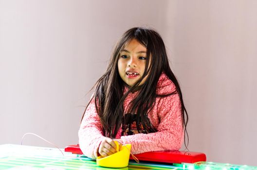 Concentrated and enthusiastic girl plays table hockey