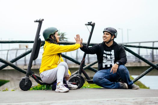 Two smiling friends showing helmet, concept in driving safety with a means of transportation