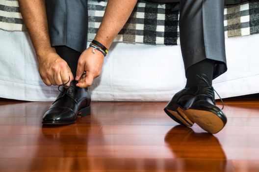 Man ties his shiney new black leather business shoes