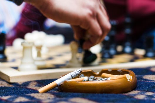 Cigar on an ashtray with the background of a game of chess