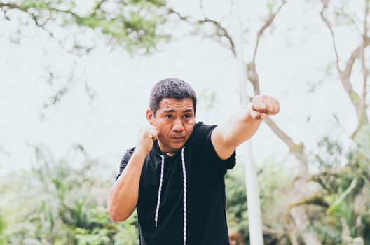 Photo of young handsome sporty fighter training outdoors in the park