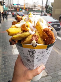 Fast street food in Lima - Peru, french fries and fried chicken with mayonnaise among other creams in a cone