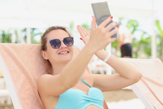 Happy woman in a swimsuit makes a selfie, close-up. Photo on vacation by the pool, summer vacation in the hotel complex