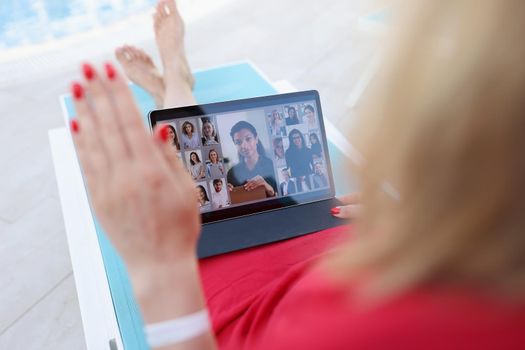 A woman is sitting by the pool with a tablet in her hands, close-up, blurry. Video communication during vacation, webinar, online training