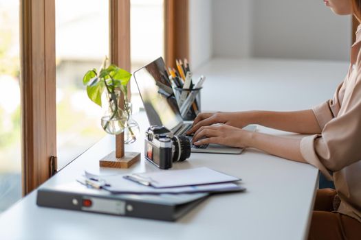Young freelance woman hands typing on keyboard on laptop computer to work at modern office.