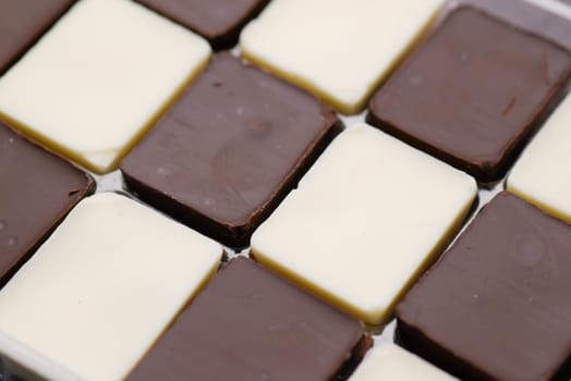dark and white chocolate in a box on gray background .
