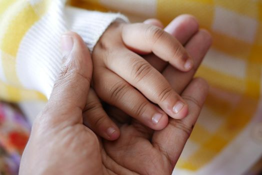 father holding hand of baby child, close up