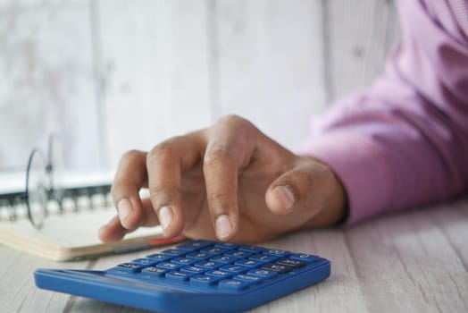 Close up of man hand using calculator.