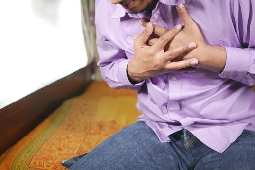 young man suffering pain in heart and holding chest with hand .