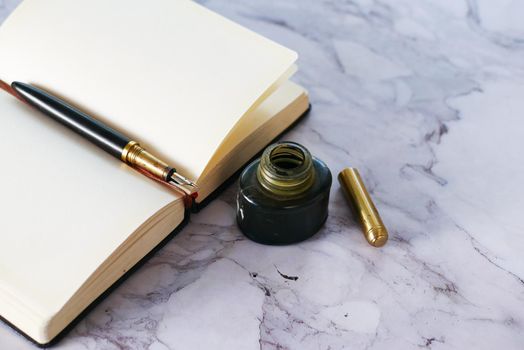 book, fountain pen and ink on table .
