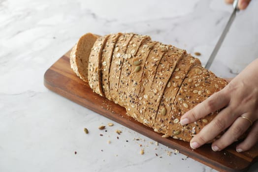 Women hand cutting baked brow bread on table