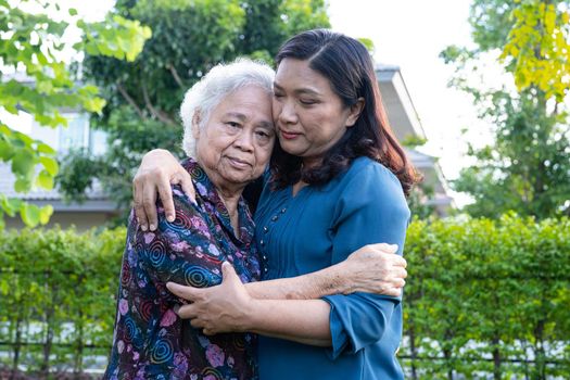 Asian elderly woman with caregiver walking with happy in nature park.