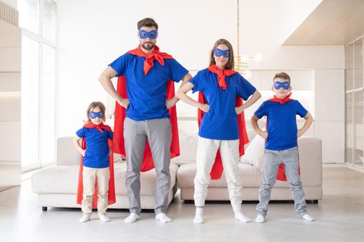 Happy family in superhero costumes plays adventure at home