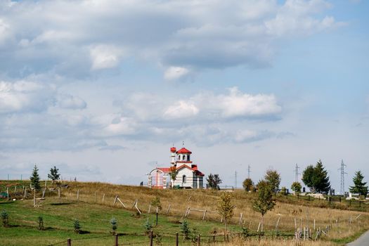 White brick church with red roof in the field. High quality photo