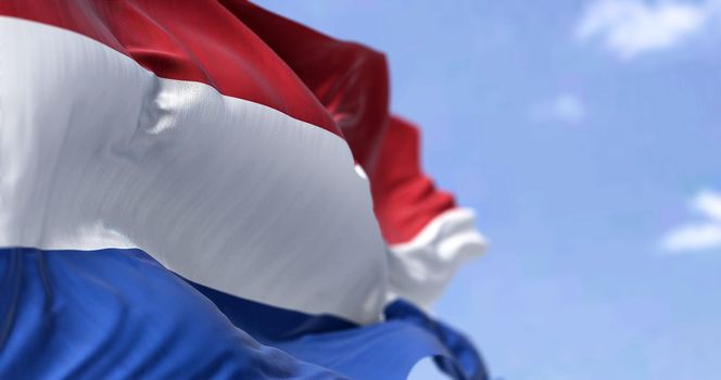 Detail of the national flag of the Netherlands waving in the wind on a clear day. Democracy and politics. European country. Selective focus.