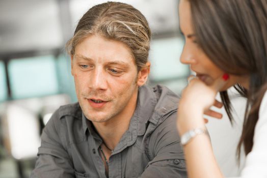 Young coworkers working together and discussing points while using computer