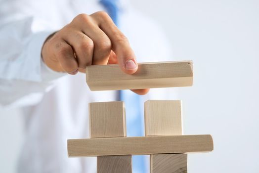 Close up of businessman building tower of wooden blocks