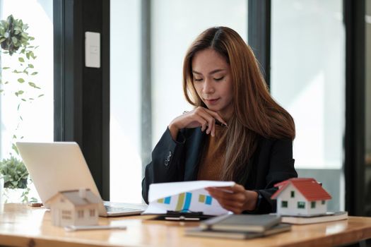 Asian business woman working for interest, taxes and profits to invest in real estate and home buying.
