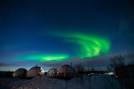 Northern Lights also known as aurora, borealis or polar lights at cold night over igloo village. Beautiful night photo of magic nature of Teriberka, Murmansk. High quality photo