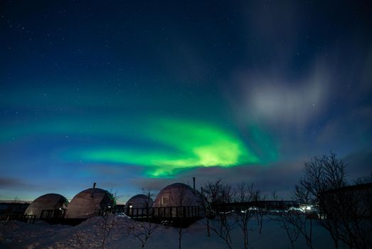 Northern Lights also known as aurora, borealis or polar lights at cold night over igloo village. Beautiful night photo of magic nature of Teriberka, Murmansk. High quality photo