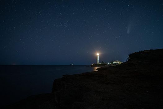 Panoramic HDR Landscape view of Neowise comet over white Lighthouse at night sky. High quality photo