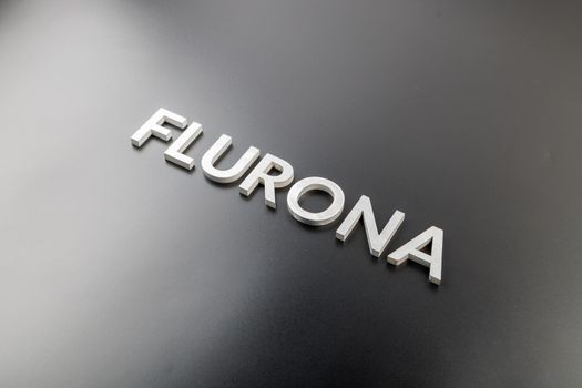 the word flurona laid with silver metal letters on gloss black background, real life photo for flu plus covid concept in diagonal perspective view
