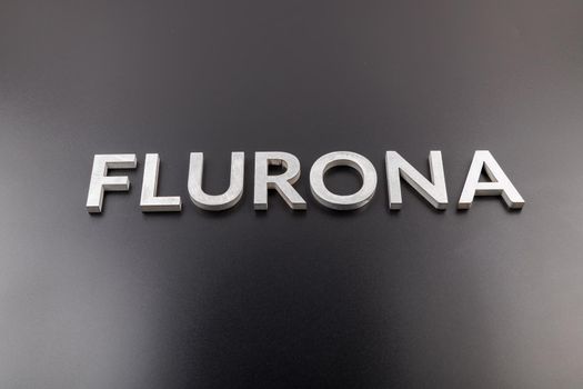 the word flurona laid with silver metal letters on gloss black background, real life photo for flu plus covid concept in frontal perspective view
