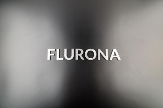 the word flurona laid with silver metal letters on gloss black background, real life photo for flu plus covid concept in high angle flat lay view