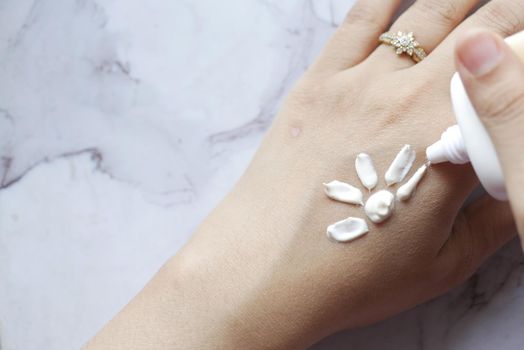women applying sunscreen cream on hand .