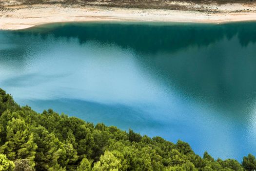 Reflections on the colorful swamp of Guadalest village surrounded by vegetation and mountains on a sunny day
