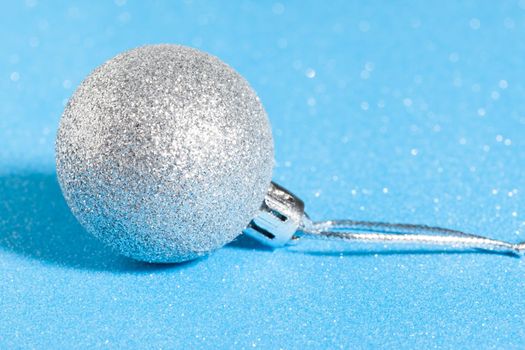 silver shiny christmas ball on sparkling blue background.