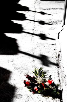 Shadow of Crosses on the ground next to a colorful bouquet in a cemetery in Spain