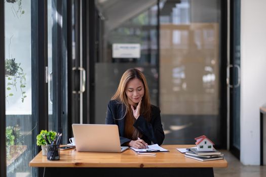 Business asian woman or real estate agent working with laptop computer at her office.