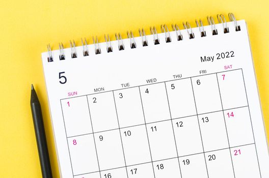 Close-up May 2022 desk calendar on yellow background.