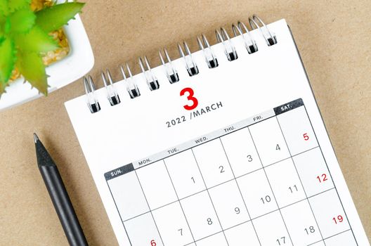 The March 2022 desk calendar on brown background.