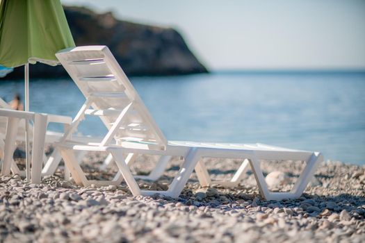 white sun loungers and an umbrella on a deserted beach. The perfect vacation concept